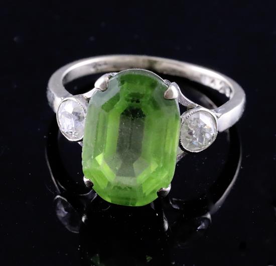 A mid 20th century 9ct white gold and oval cut peridot ring with diamond set shoulders, size M.